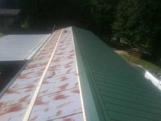 Old rusted panels beside newly installed green metal roofing — Wind Damage Roof Repair by Roofing Brothers in Bellflower