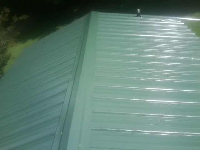 New green metal panels meeting at the ridge of a roof — Flat Roof Repair work by our crew in Bellflower