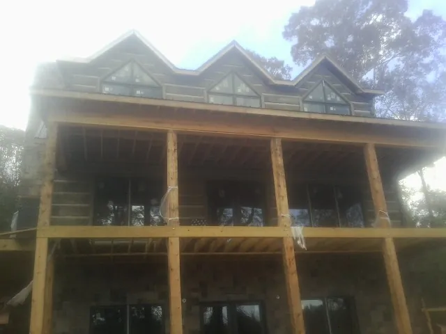 Dormers and porch framing on a large log home under construction — Roof Coating work by our crew in Bellflower
