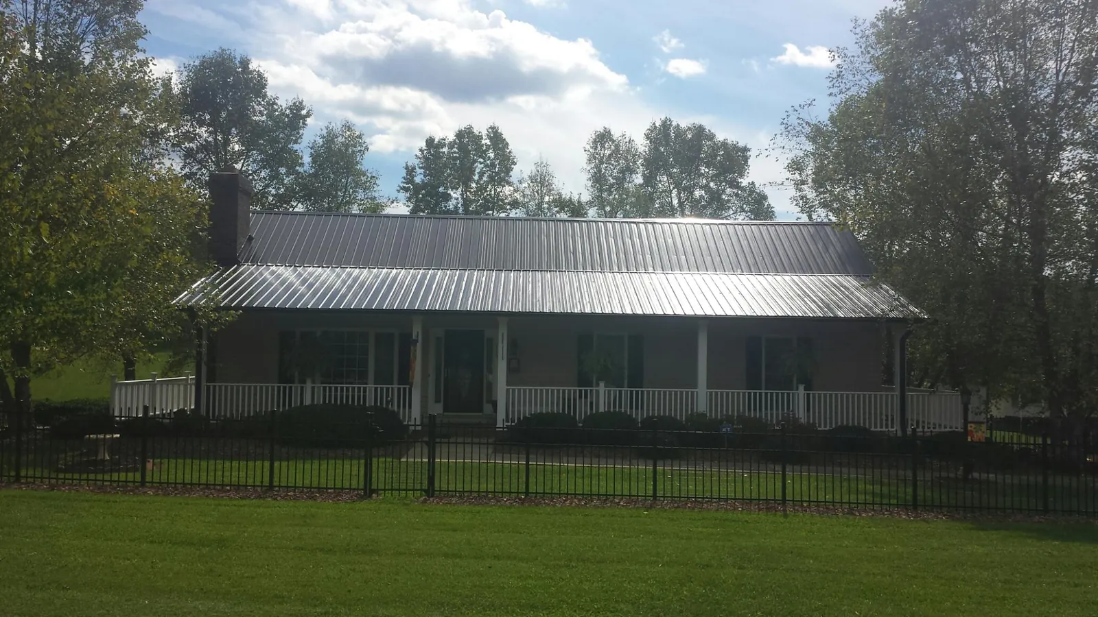 Gray metal roof on a brick ranch with a full width front porch — Gutter Guard Installation work by our crew in Bellflower