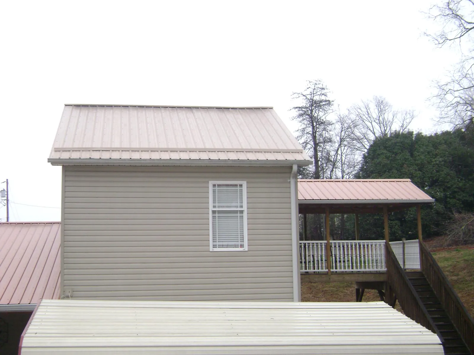Tan metal roofs on a two story addition and attached porch, from a Roof Replacement job in Bellflower